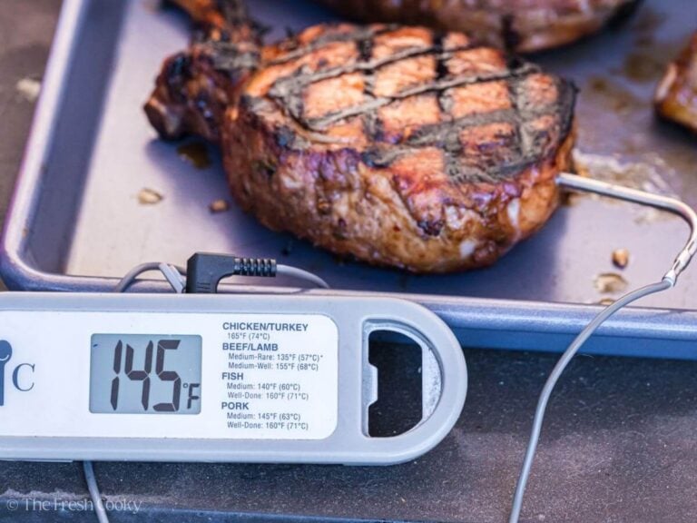 Pork chop on a sheet pan showing an internal temp of 145 degrees.