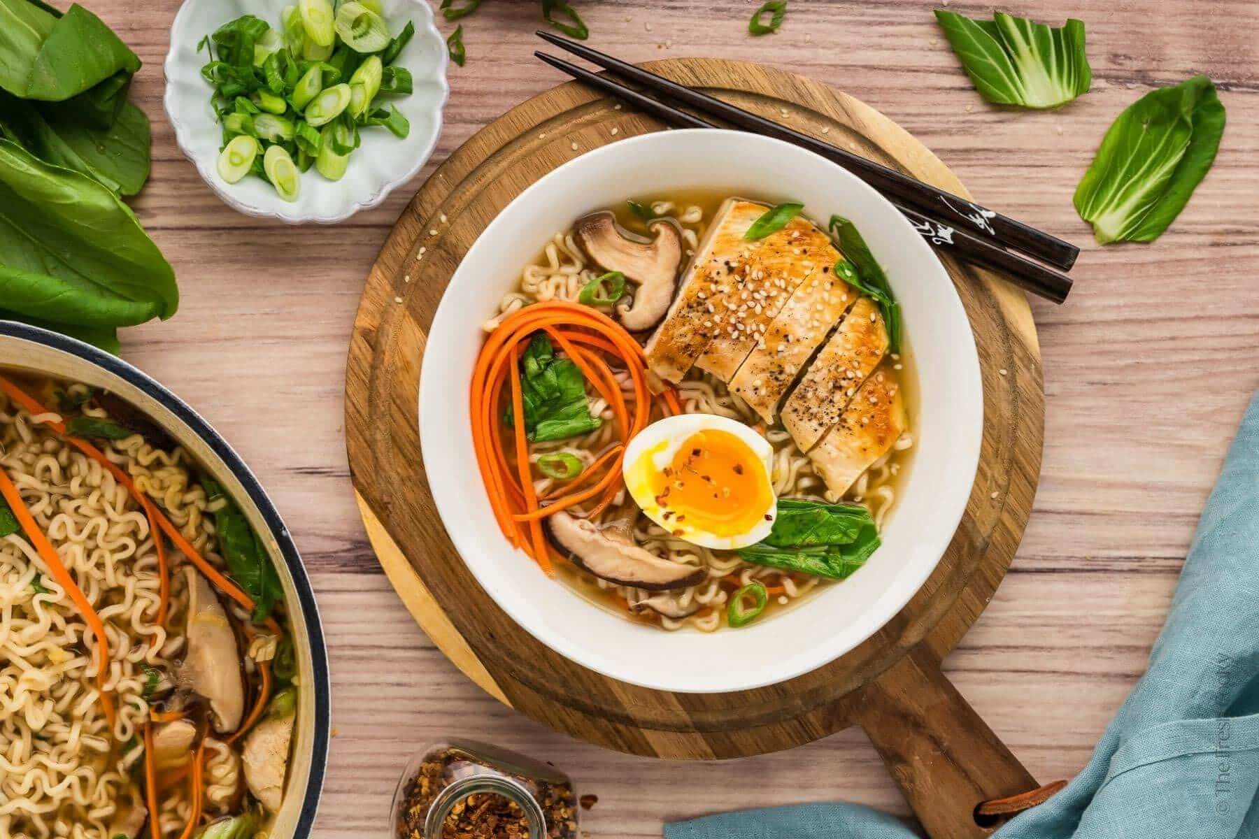 Overhead shot of ramen in a white bowl on a wooden background.