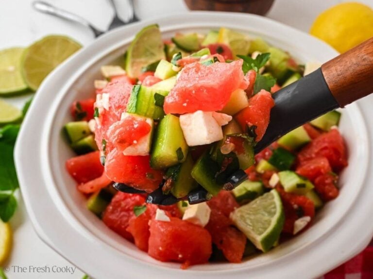 Spoon scooping up a portion of watermelon cucumber salad from a bowl.