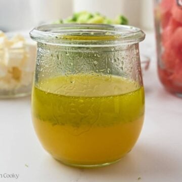 Side view of the dressing ingredients in a small glass jar.