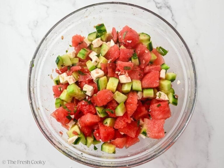 Watermelon cucumber salad all mized together with the dressing in a large bowl.