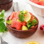 Side view of watermelon cucumber salad in a small wooden bowl.