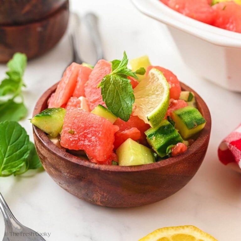 Side view of watermelon cucumber salad in a small wooden bowl.