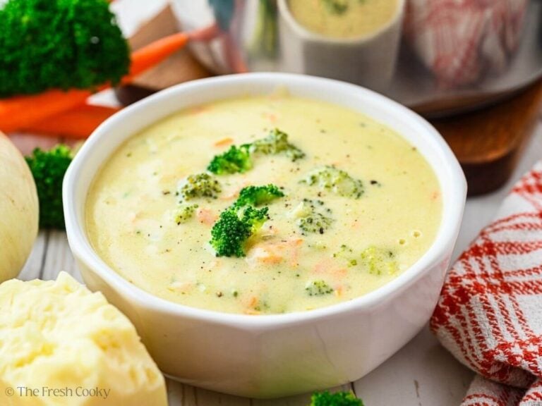 Bowl of broccoli cheese soup with extra broccoli florets on top.