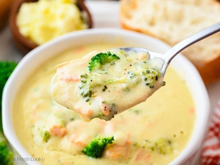 Spoonful of broccoli cheese soup hovering over a bowl of soup.