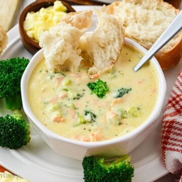 Bowl of broccoli cheese soup with bread being dipped in.