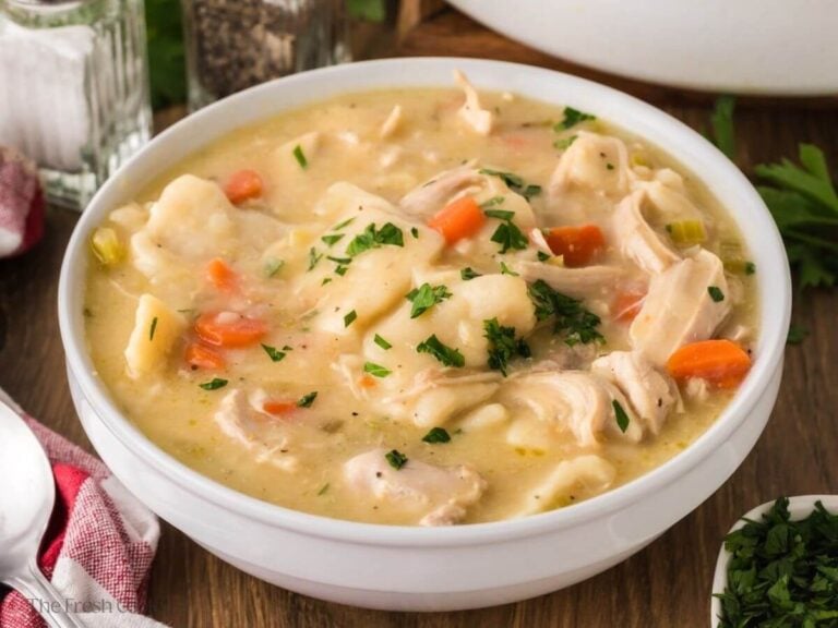 Bowl of cracker barrel chicken and dumplings topped with parsley.