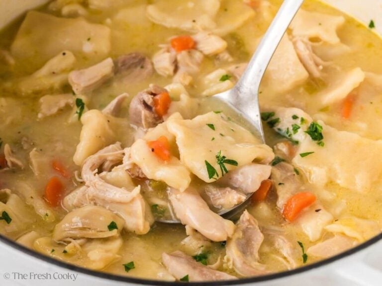 Spoon scooping up some cracker barrel chicken and dumplings from a pot.