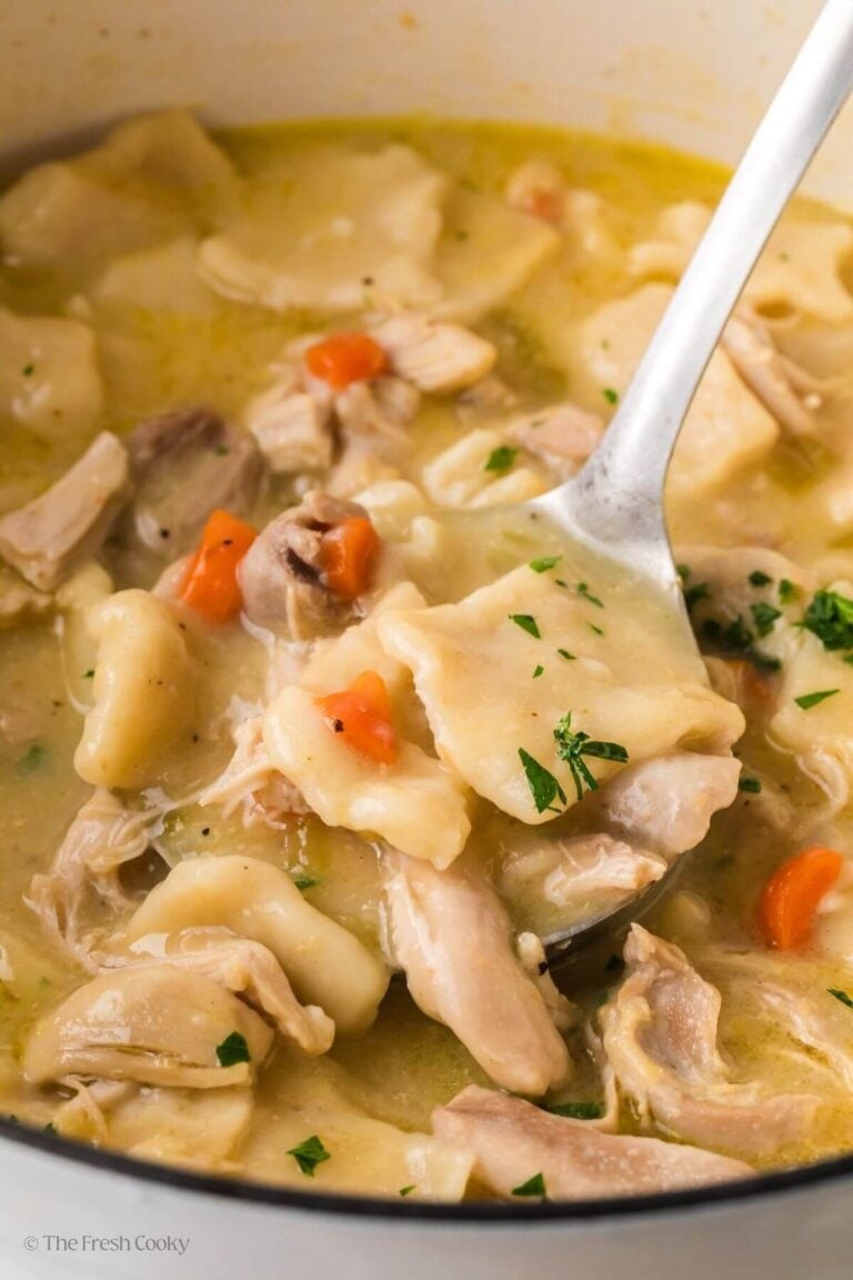 Spoon of cracker barrel chicken and dumplings taking a portion from a pot.