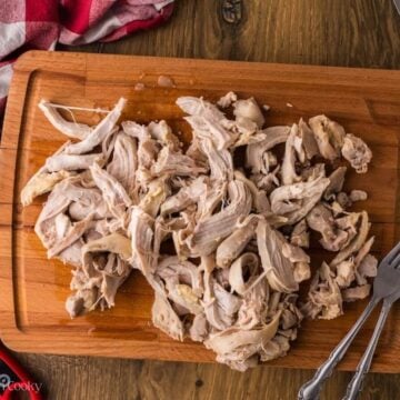 Shredded chicken on a wooden cutting board.