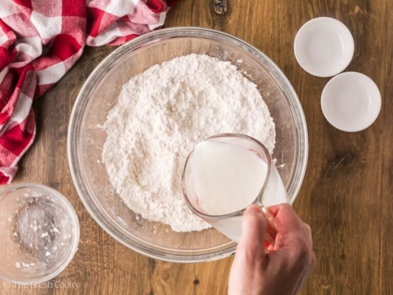 Adding buttermilk to the flour and butter mixture in a bowl.