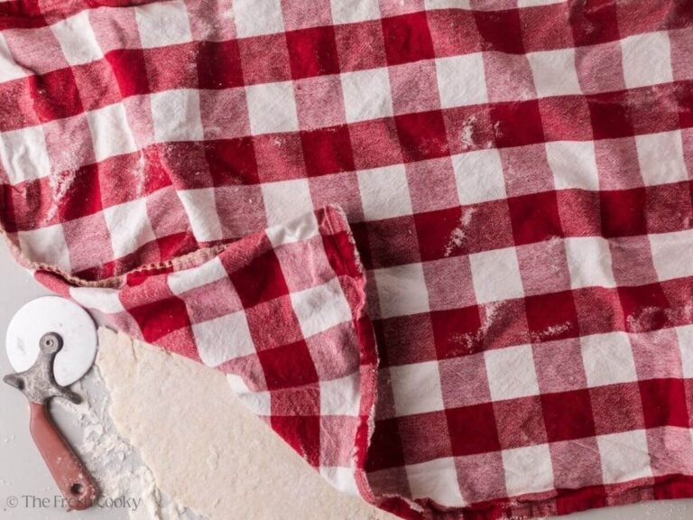 Placing a linen over the top of dumpling dough.