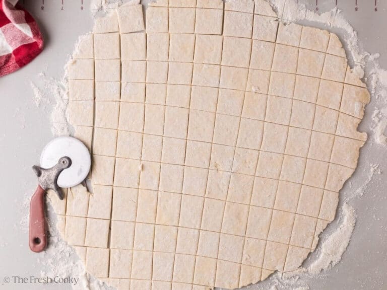 Using a pizza cutter to slice the dumplings into squares.