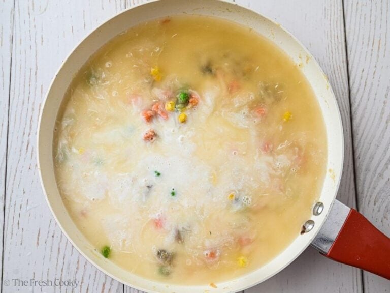 Milk and garlic mixture with chicken broth added to a skillet.