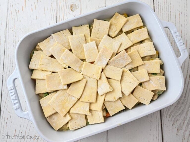 Squares of puff pastry placed over the chicken pot pie filling in a baking dish.