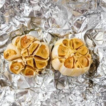 Two bulbs of roasted garlic in foil.