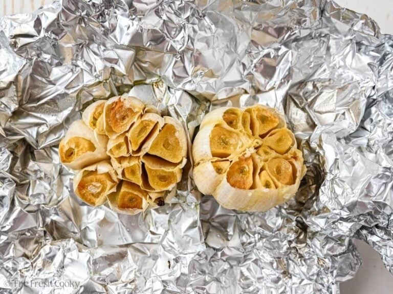 Two bulbs of roasted garlic in foil.