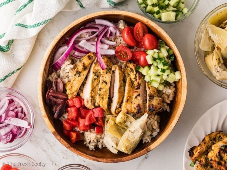 Cucumber, tomatoes, onion, cucumber, peppers, and artichokes added to the bowl with rice and chicken.