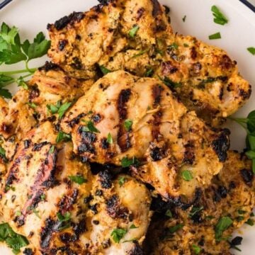 Looking down on a plate with grilled chicken thighs that were marinated in a Greek yogurt marinade.