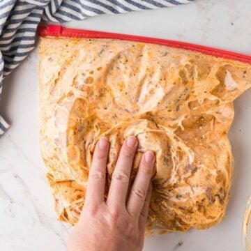 Hand squishing marinade into the chicken.