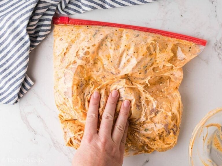 Hand squishing marinade into the chicken.
