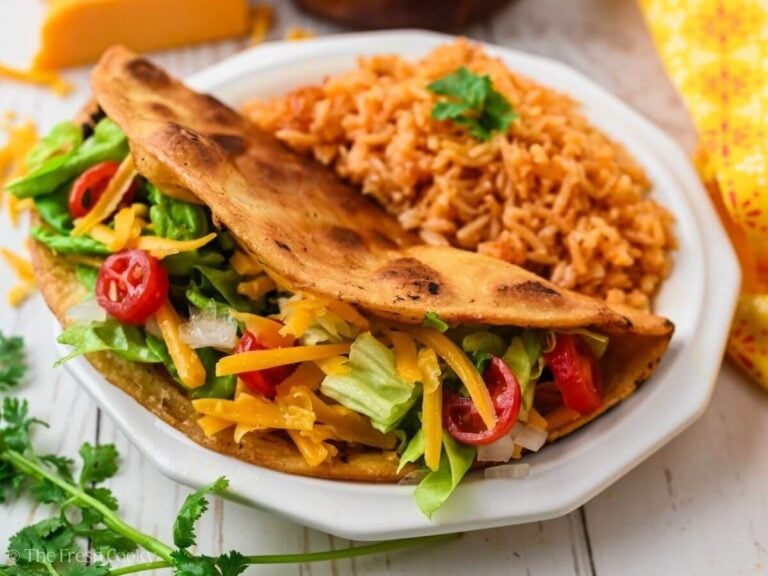 Ground beef taco served on a plate with a side of Mexican rice.