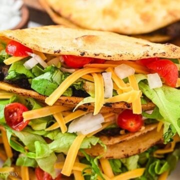 Close up of ground beef tacos stacked on each other.