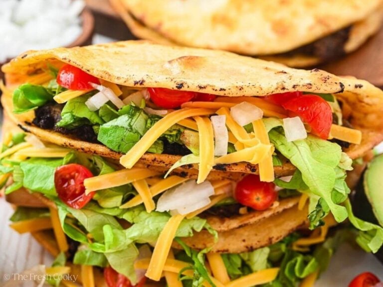 Close up of ground beef tacos stacked on each other.