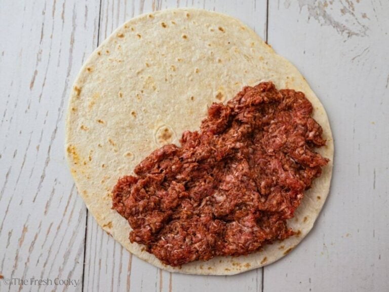 Taco seasoned ground beef pressed on top of half of a tortilla.