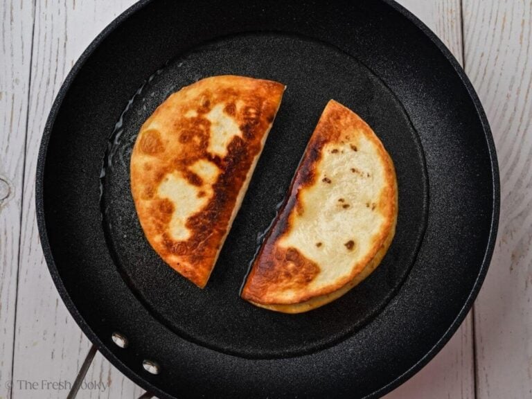 Ground beef tacos cooking in oil flipped over.