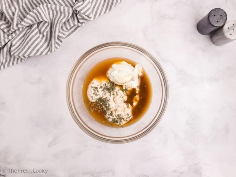 Broth, spices, cream of mushroom soup, and sour cream in a bowl.