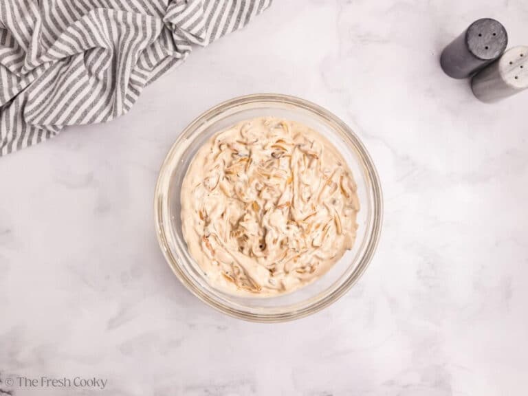 Onions folded into the cream of mushroom mixture in a bowl.