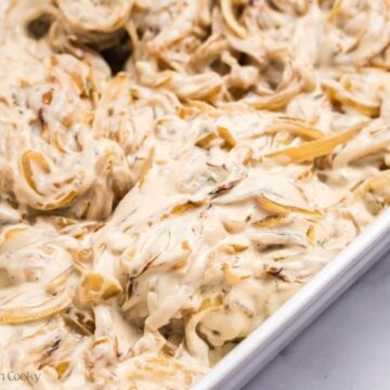 Pork chops topped with cream of mushroom mixture in a baking dish.