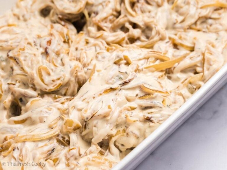 Pork chops topped with cream of mushroom mixture in a baking dish.