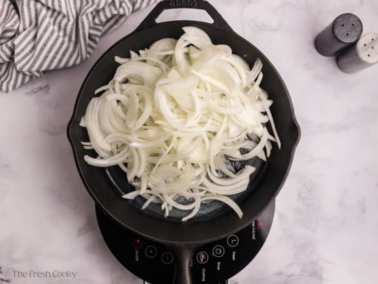 Sliced onions in a skillet to cook.