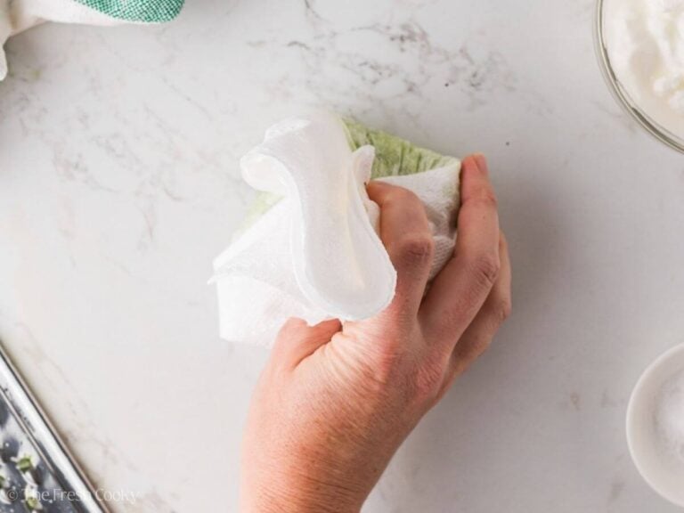 Squeezing the moisture out of grated cucumber with paper towels.