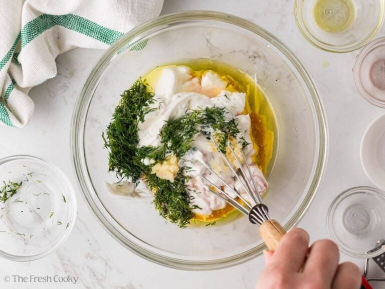 Whisking together the tzatziki ingredients in a bowl.