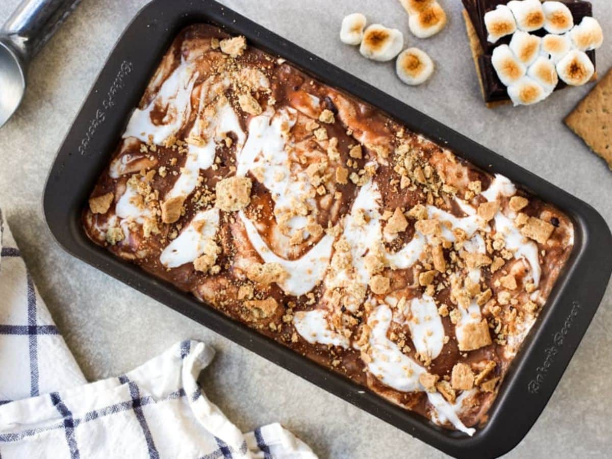 A loaf pan filled with creamy s'mores ice cream, swirled with marshmallow cream, graham crackers and chocolate.