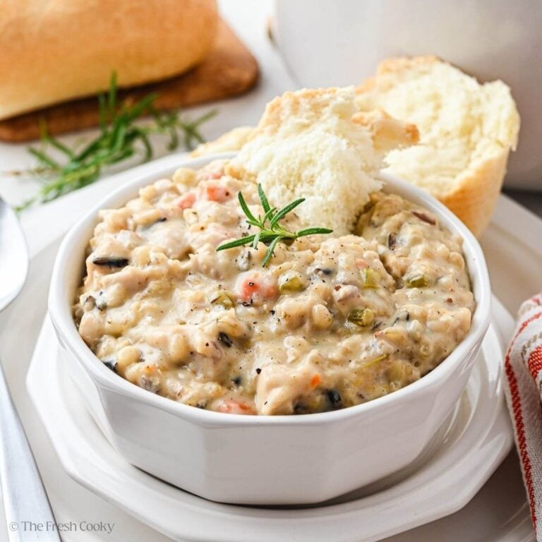Finished wild rice soup served in a bowl with bread on the side.