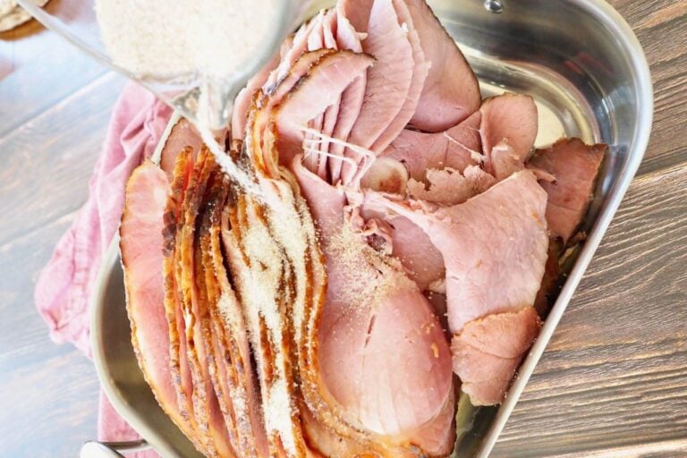 Pouring spiced sugar mixture over top of warmed ham in roasting pan to go into oven.