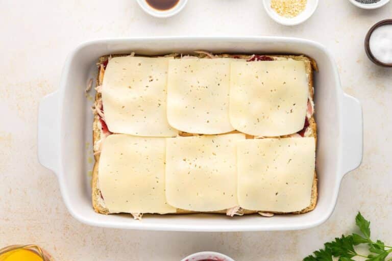Cheese layer spread on rolls for easy baked turkey sliders.