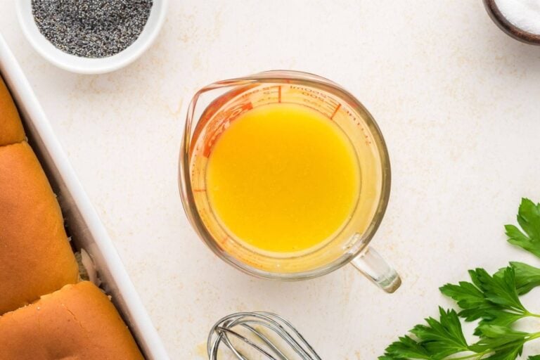 Measuring cup shown with melted butter surrounded by other ingredients.