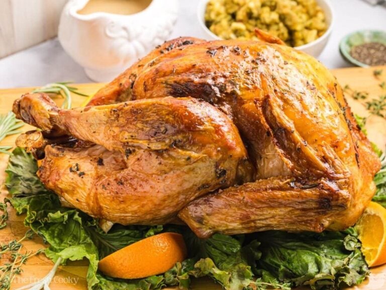 Side view of roasted herb butter turkey on a wooden board.