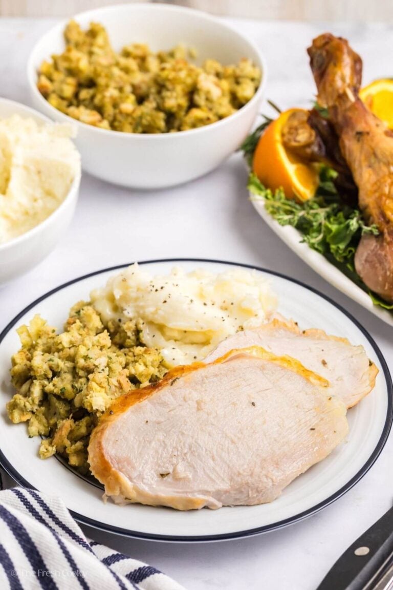 Plate of two slices of turkey with mashed potatoes and stuffing on the side.