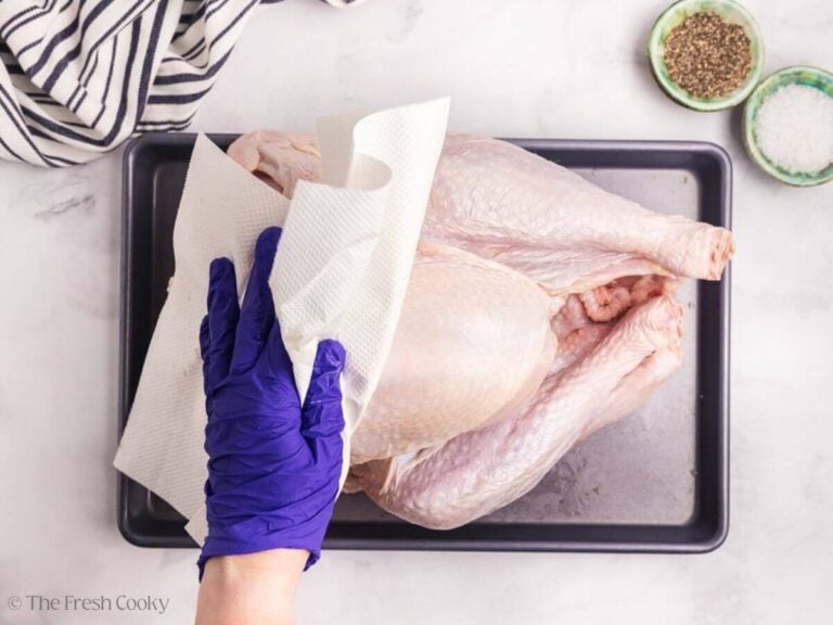 Patting a whole raw turkey dry with paper towels.