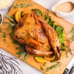 Herb butter turkey after being roasted placed on a wooden board.