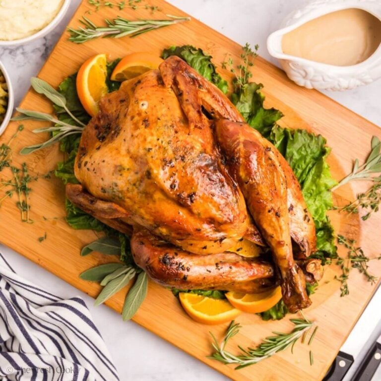 Herb butter turkey after being roasted placed on a wooden board.
