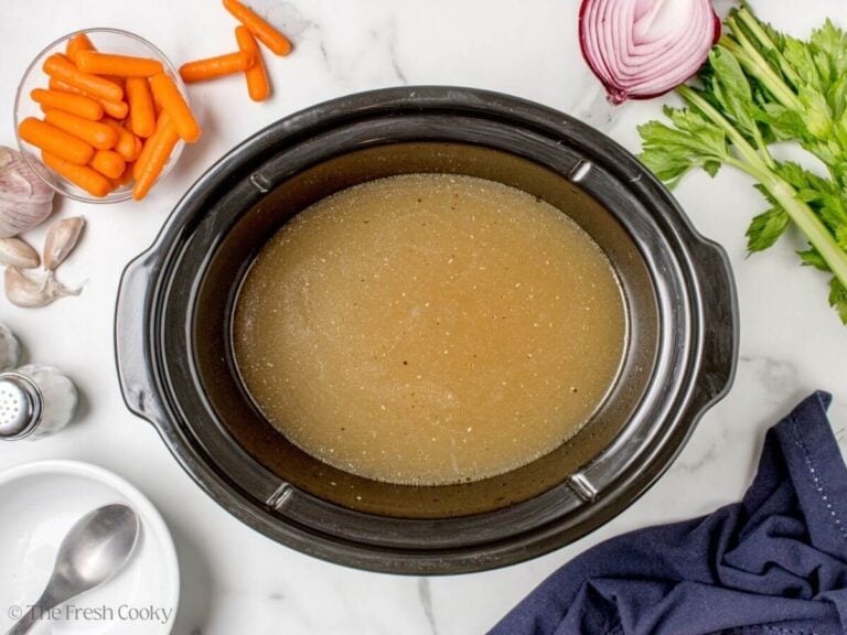 Homemade chicken stock in a black crockpot.