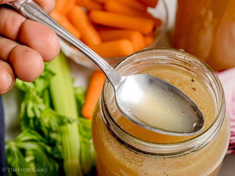 Spoon scooping up a bite of homemade chicken broth from a jar.