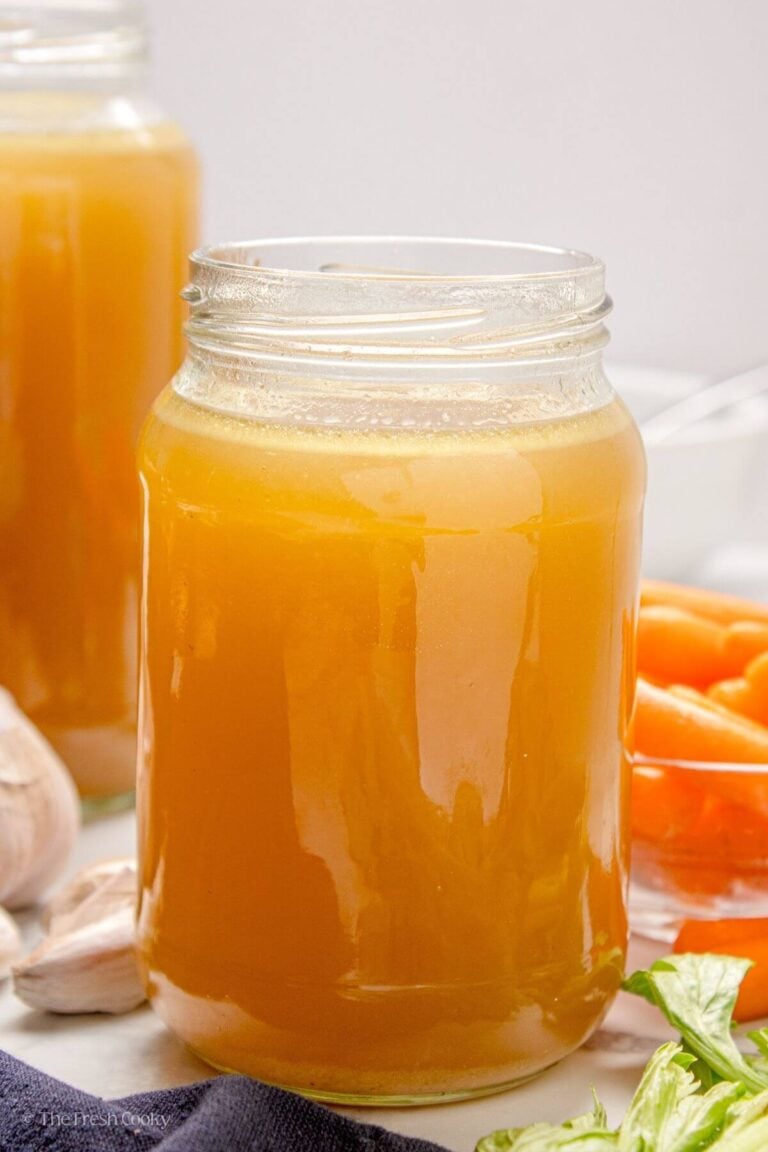 Side view of a large jar filled with slow cooker chicken broth.